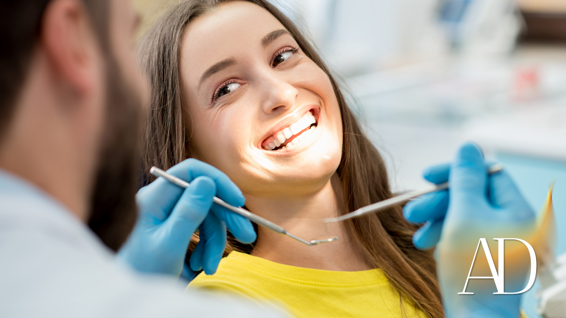 Dentist examining a smiling patient with dental tools in a clinic, wearing blue gloves