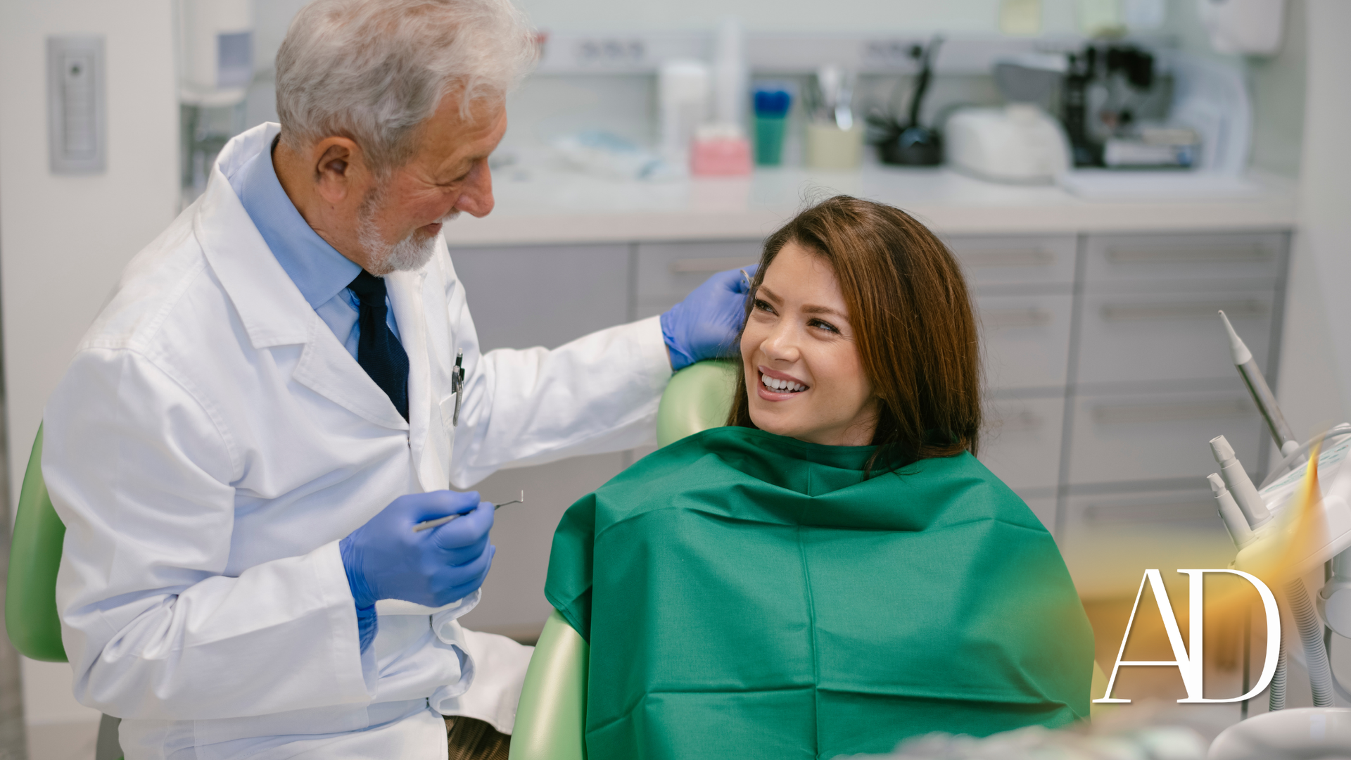 Dentist in white coat and blue gloves examining smiling patient in green bib at clinic