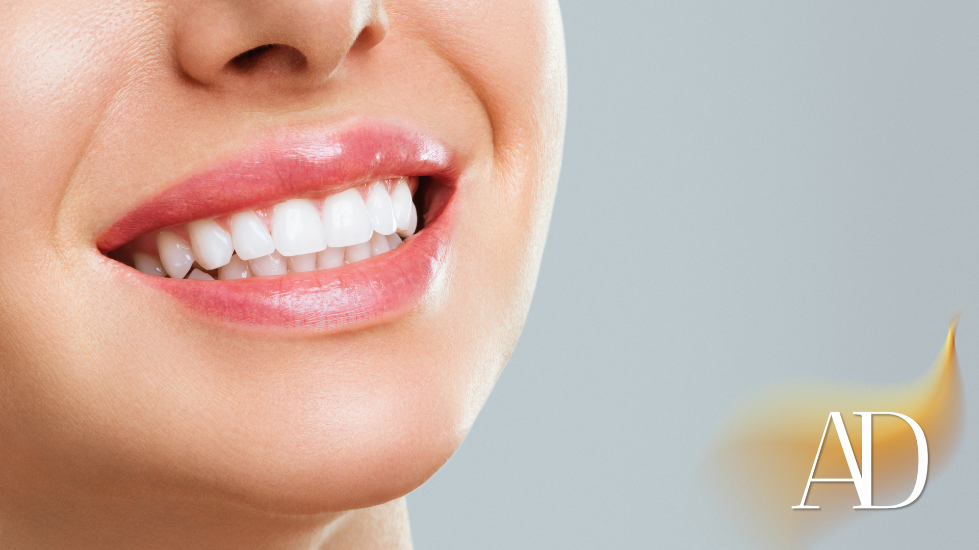 Close-up of a smiling mouth with white teeth and pink lips, with an “AD” mark in the corner