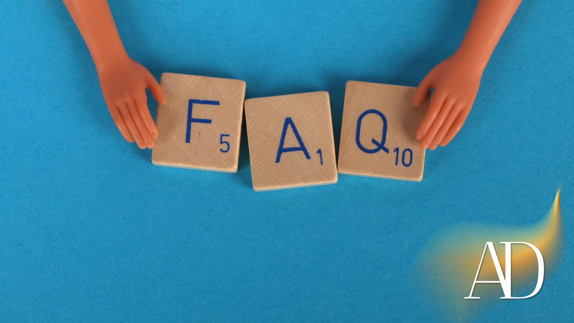 Hands holding wooden tiles spelling FAQ on a blue background