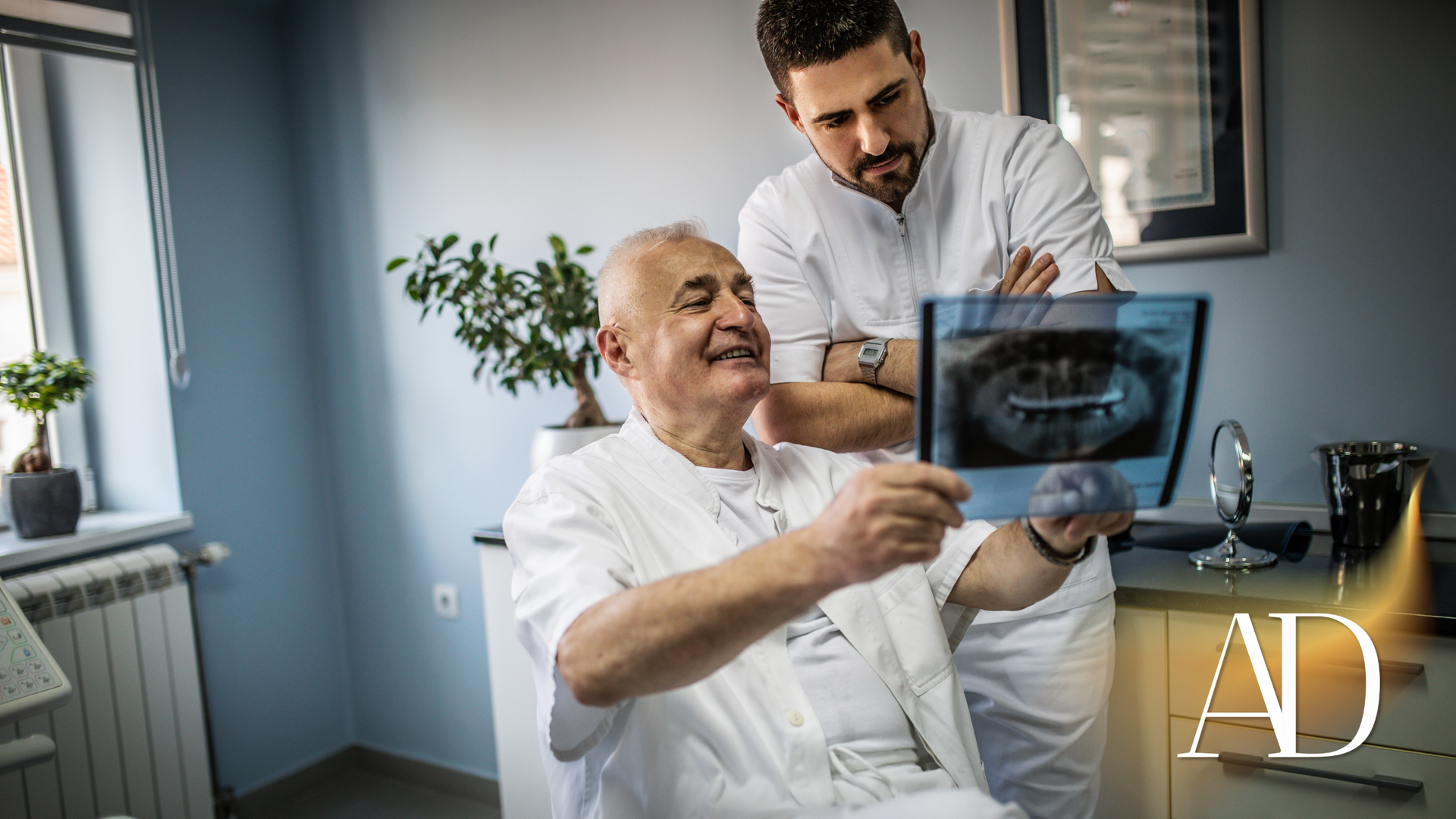 Patient holding an X-ray while clinician stands beside him in a medical office