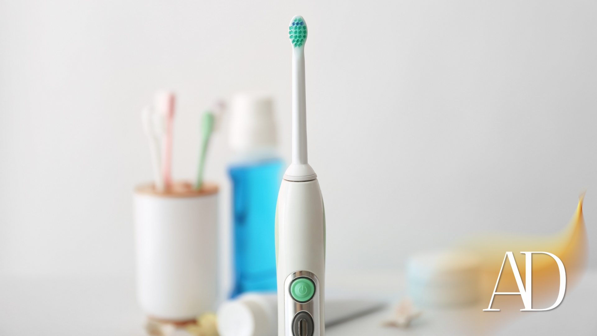 Electric toothbrush standing upright on a bathroom counter with blurred toiletries in the background