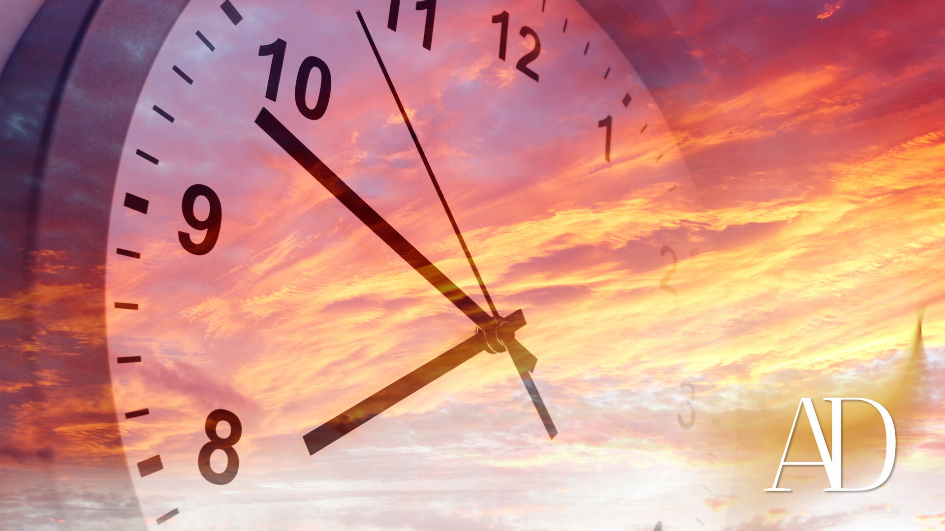 Clock face over a pink-orange sunset sky with “AD” in the lower right