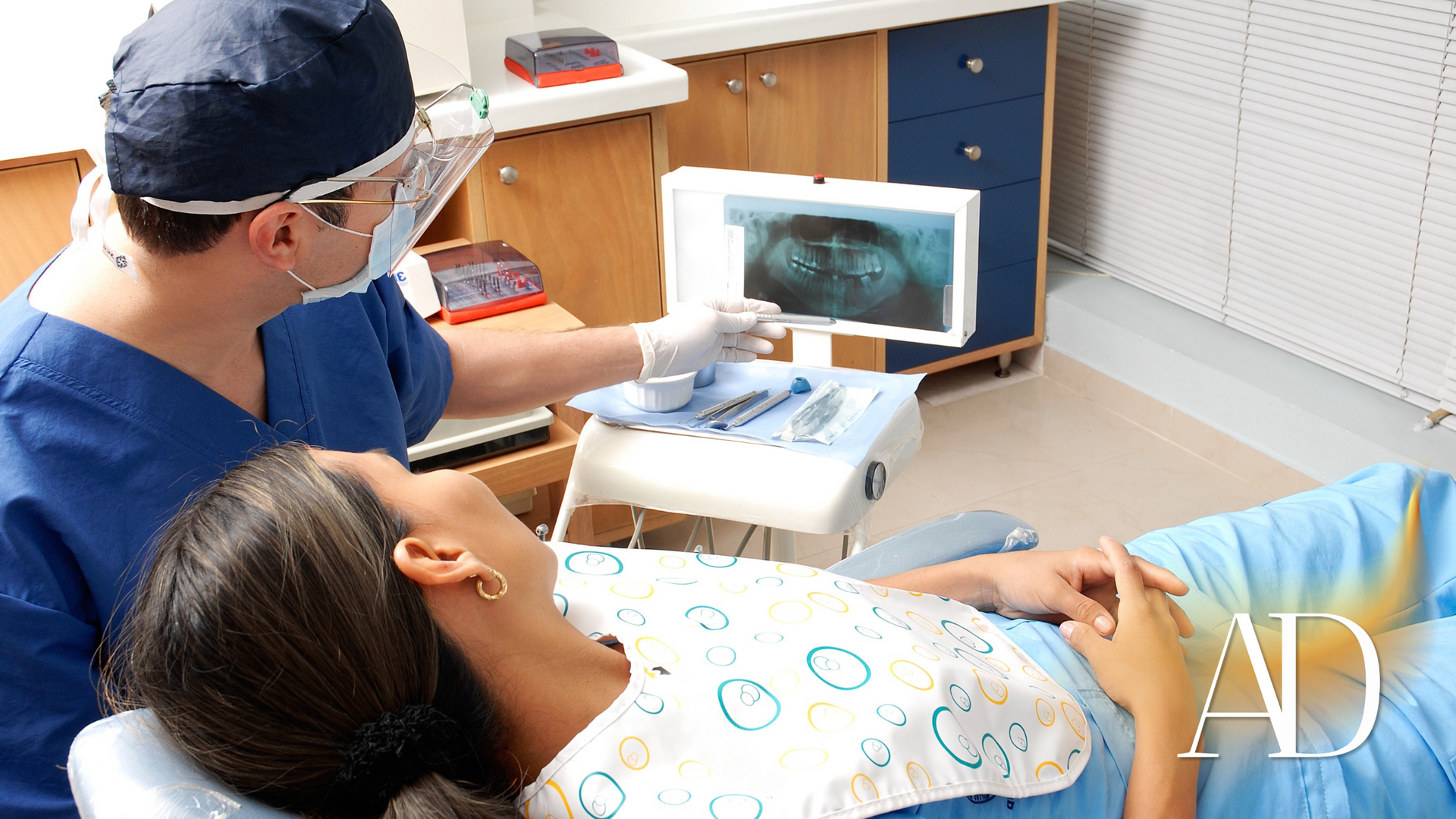 Dentist examining a patient in a clinic while viewing a monitor beside the chair