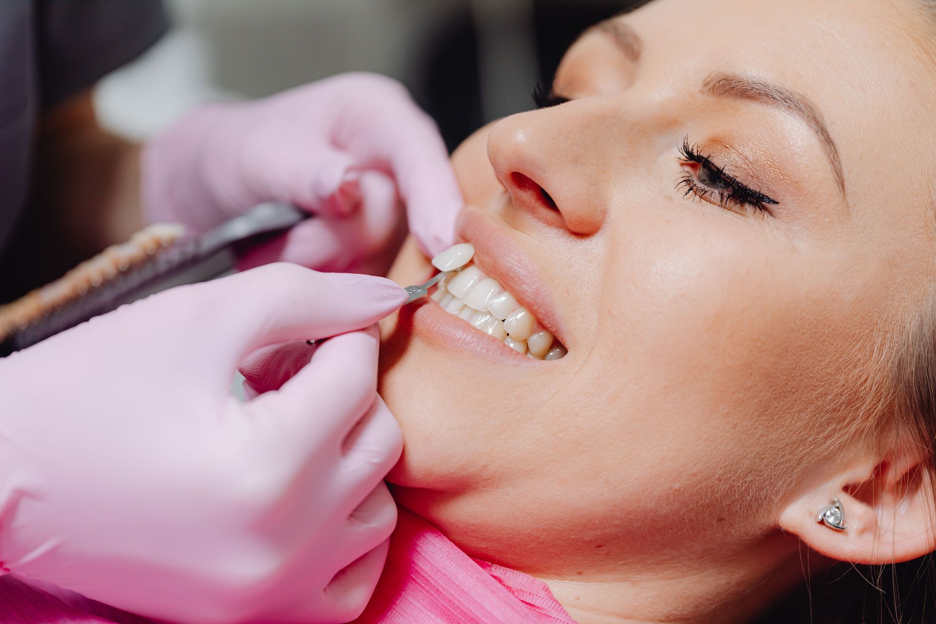 Dentist adjusting braces on a smiling patient with pink gloves