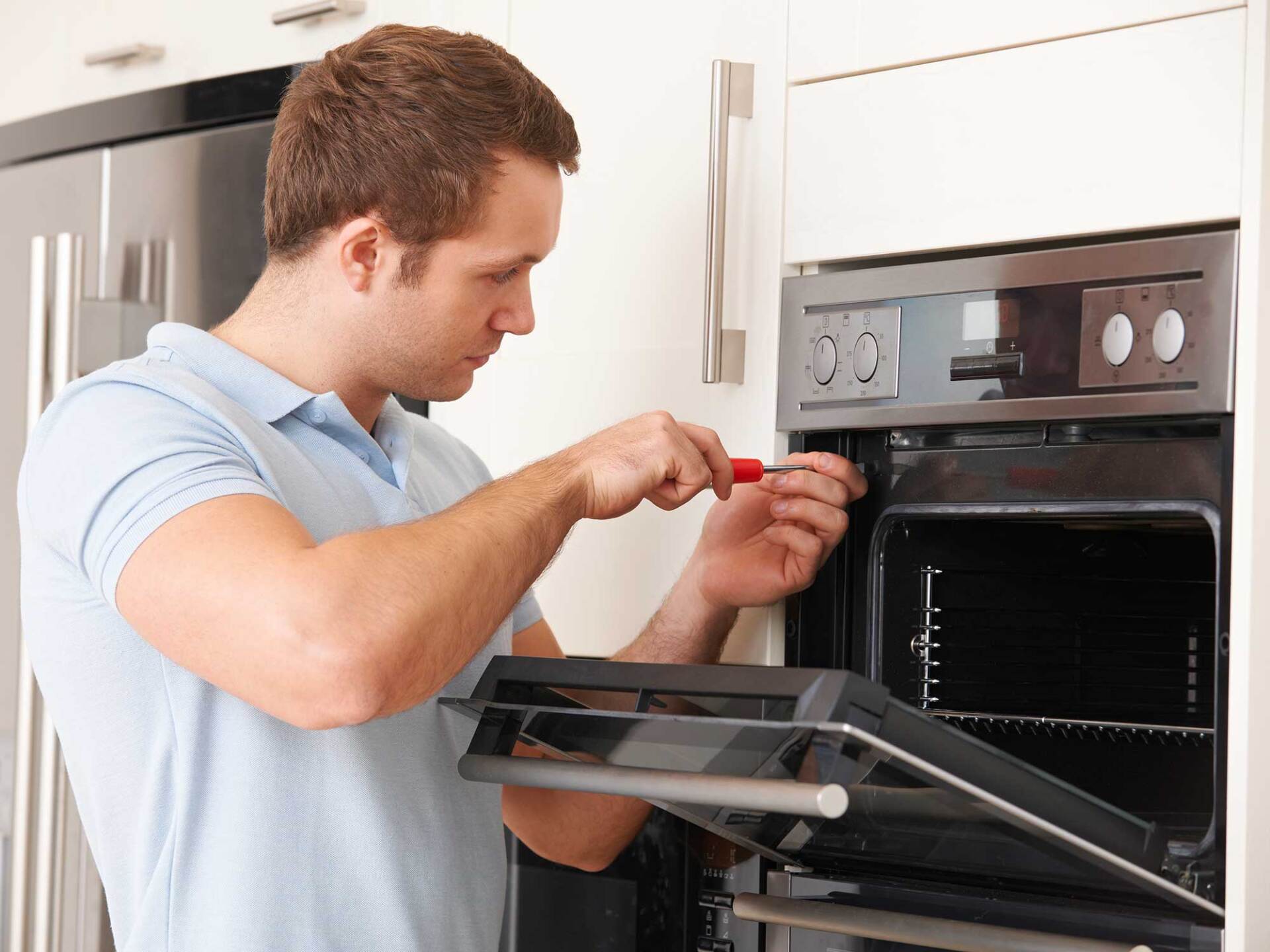 Man Repairing Oven — Anchorage, AK — Refrigeration & Food Equipment Inc Man Repairing Oven — Anchorage, AK — Refrigeration & Food Equipment Inc