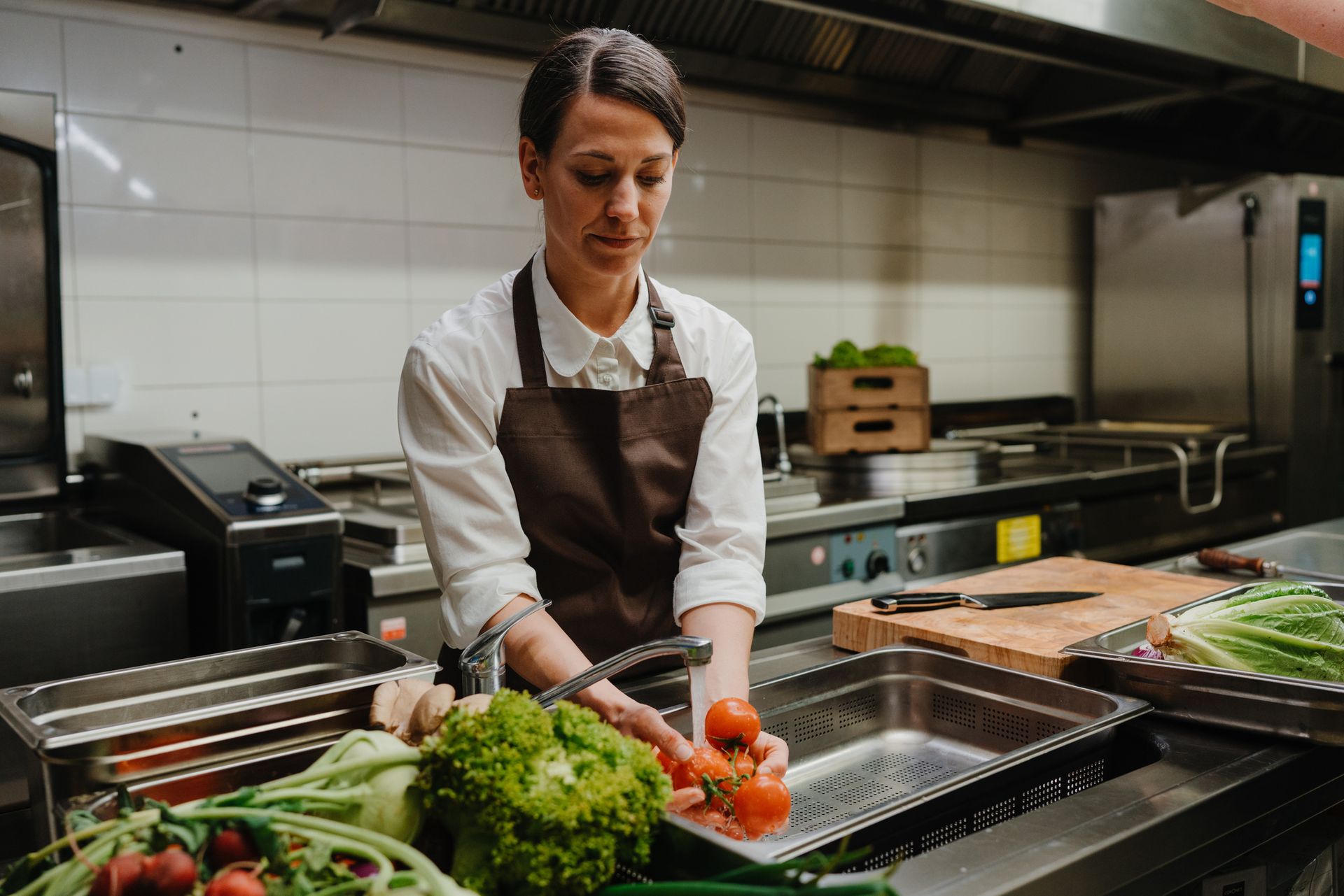 Woman in restaurant kitchen washing fresh vegetable. Woman in restaurant kitchen washing fresh vegetable.