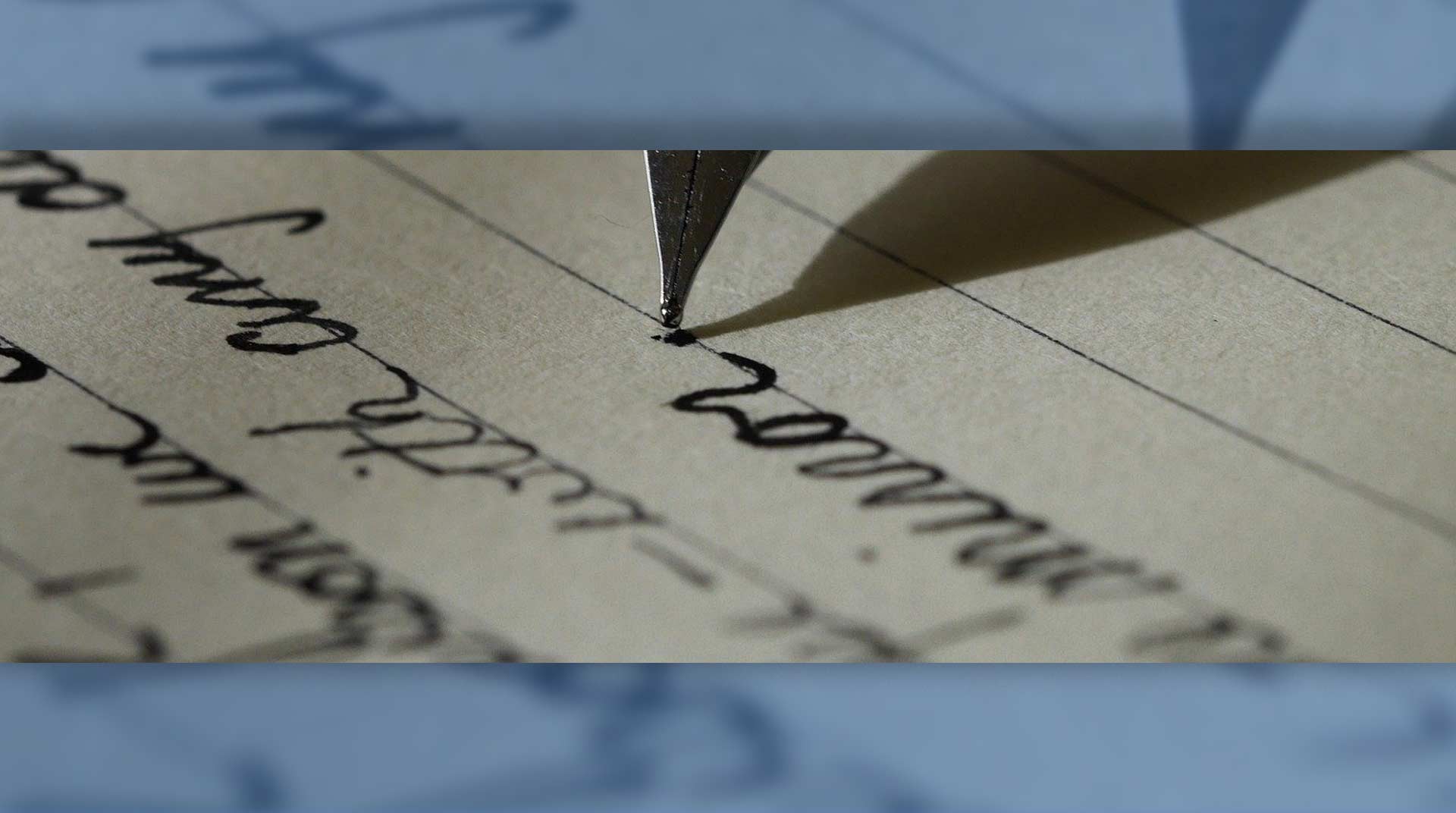 Close-up of a pen writing on lined paper, with blurred cursive notes in the background.