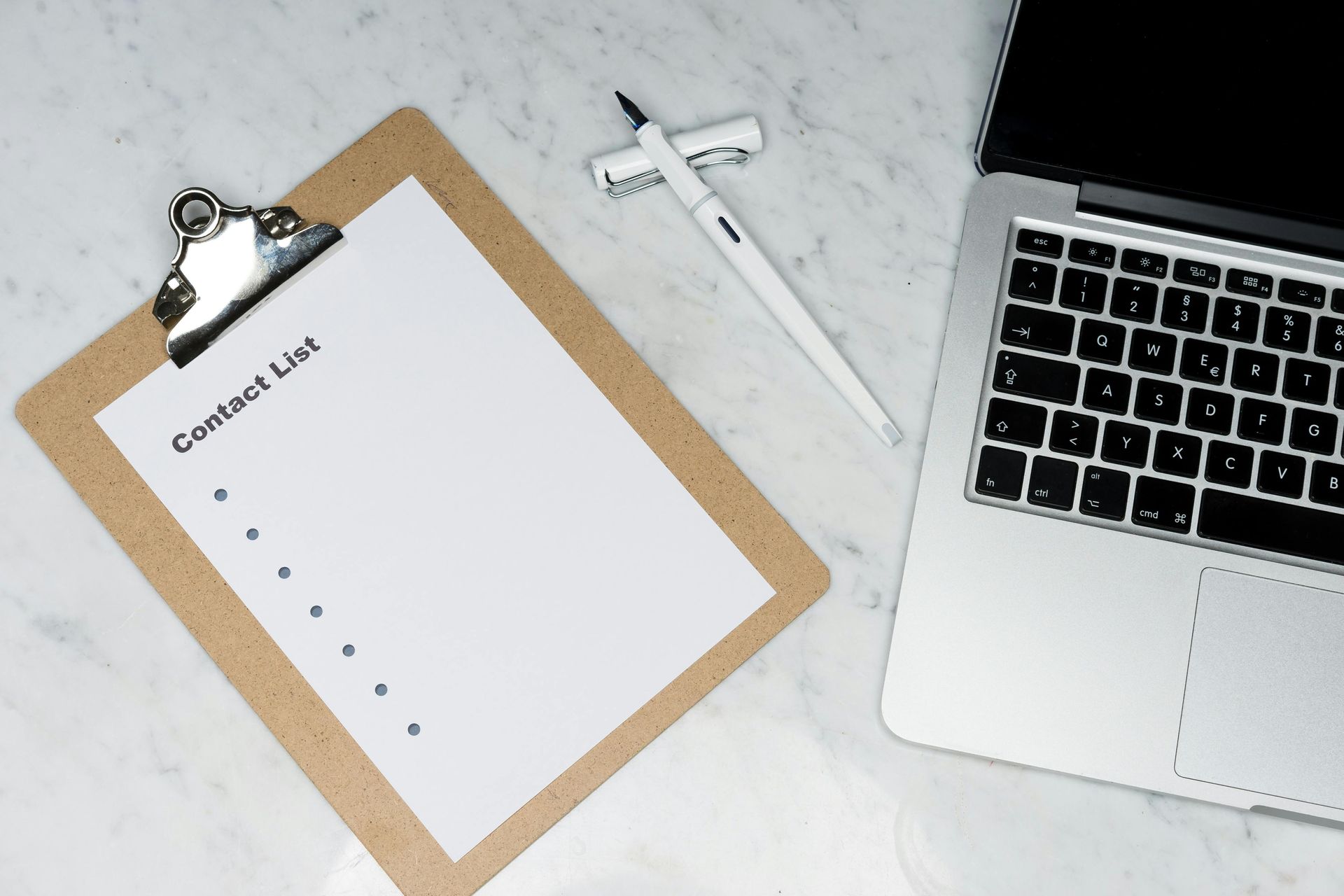 Clipboard checklist beside laptop and pen on a white desk