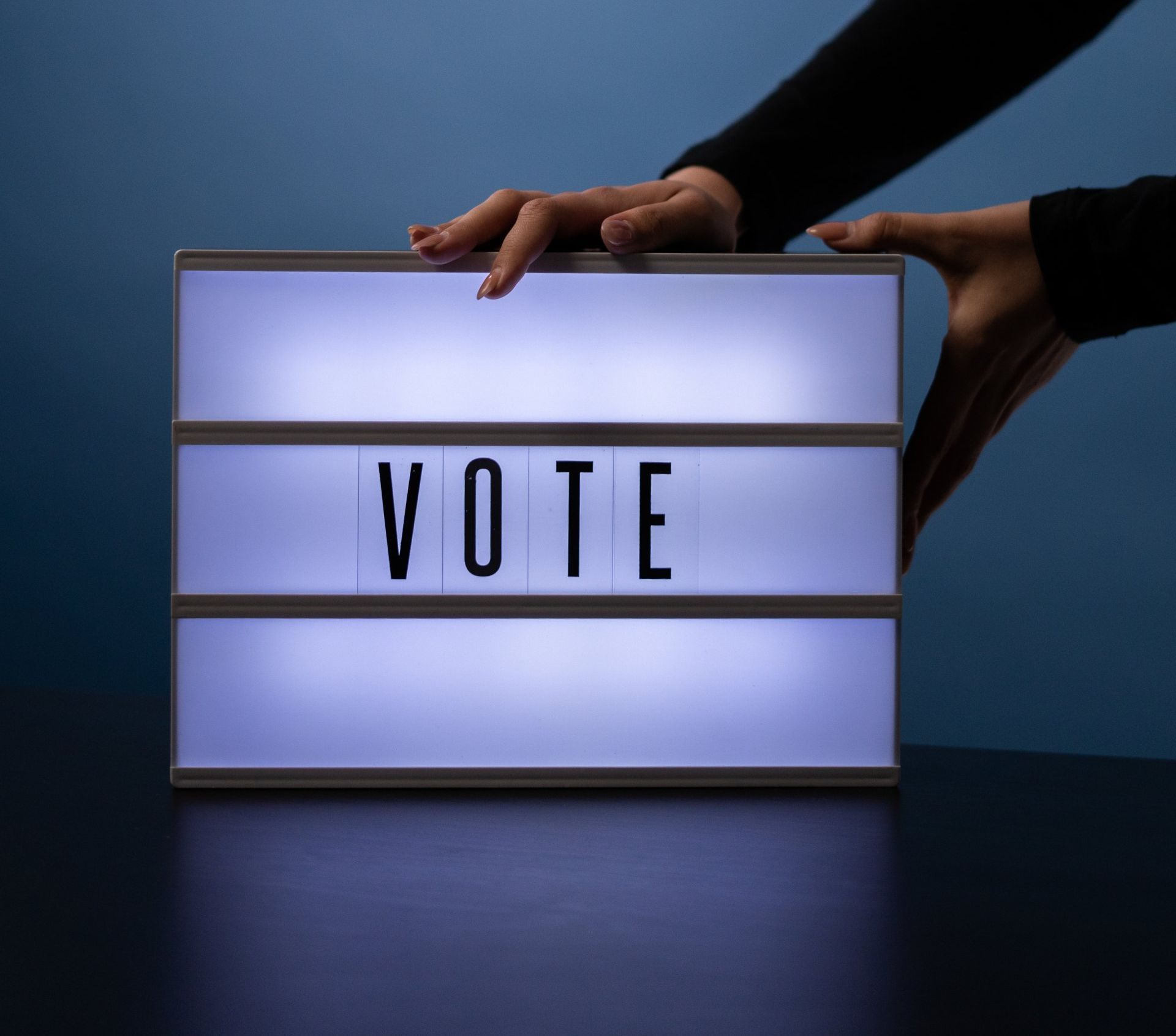 Hands holding a glowing lightbox displaying the word 