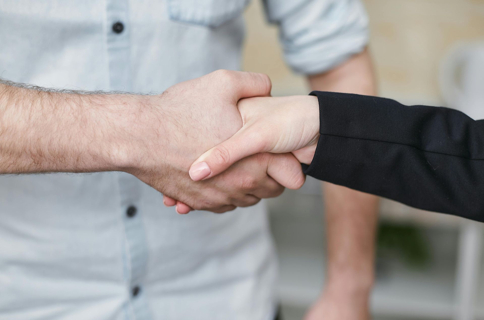 Two people shaking hands, one in a light shirt and one in a black sleeve