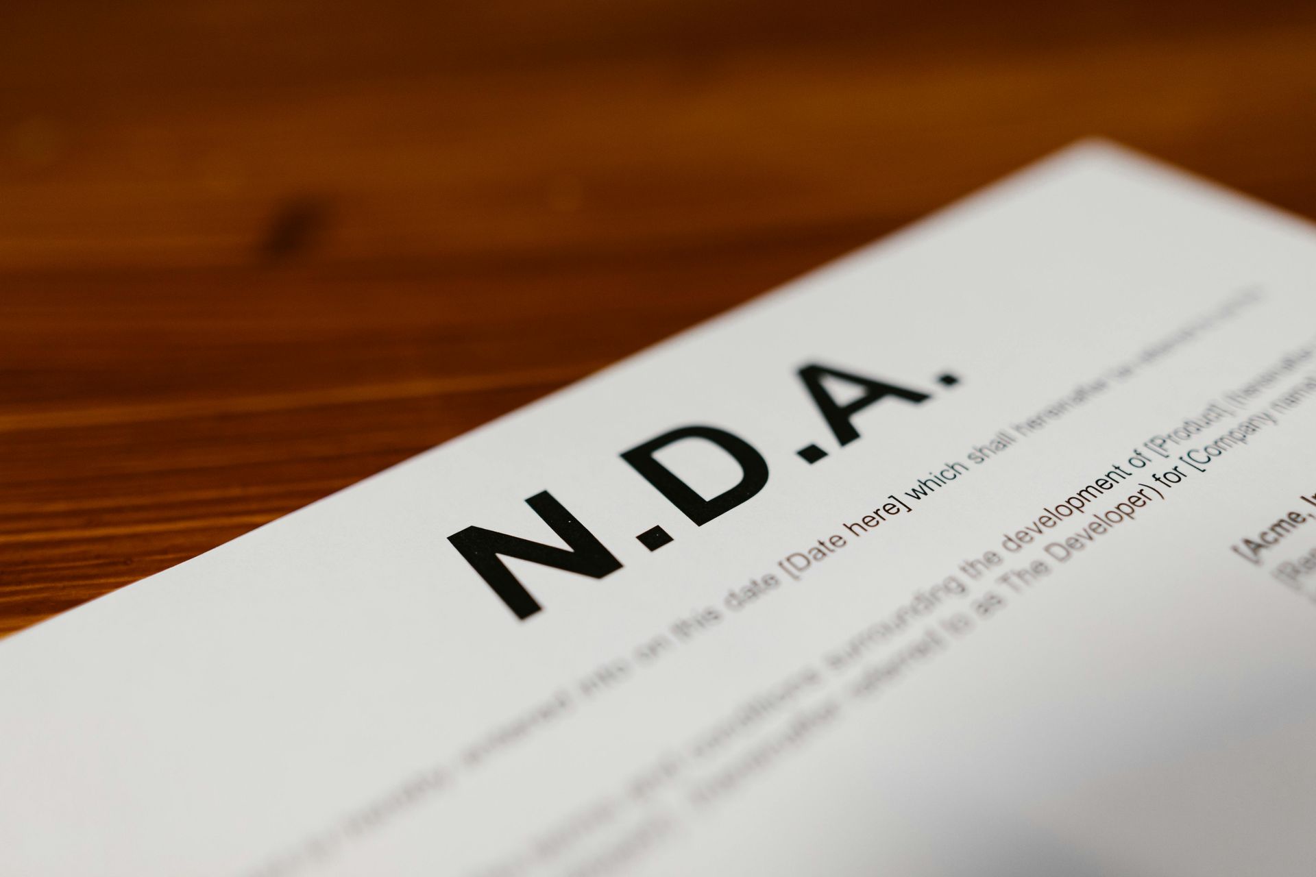 Blank NDA document on a wooden desk, with bold “N.D.A.” text visible in the foreground