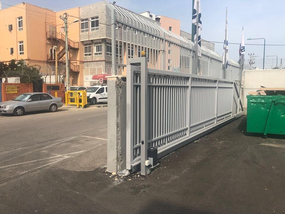 מנוף מניף שער מתכת גדול בשטח ההתארגנות, במסגרת ייצור והרכבה של שערים חשמליים כבדים וקלים.