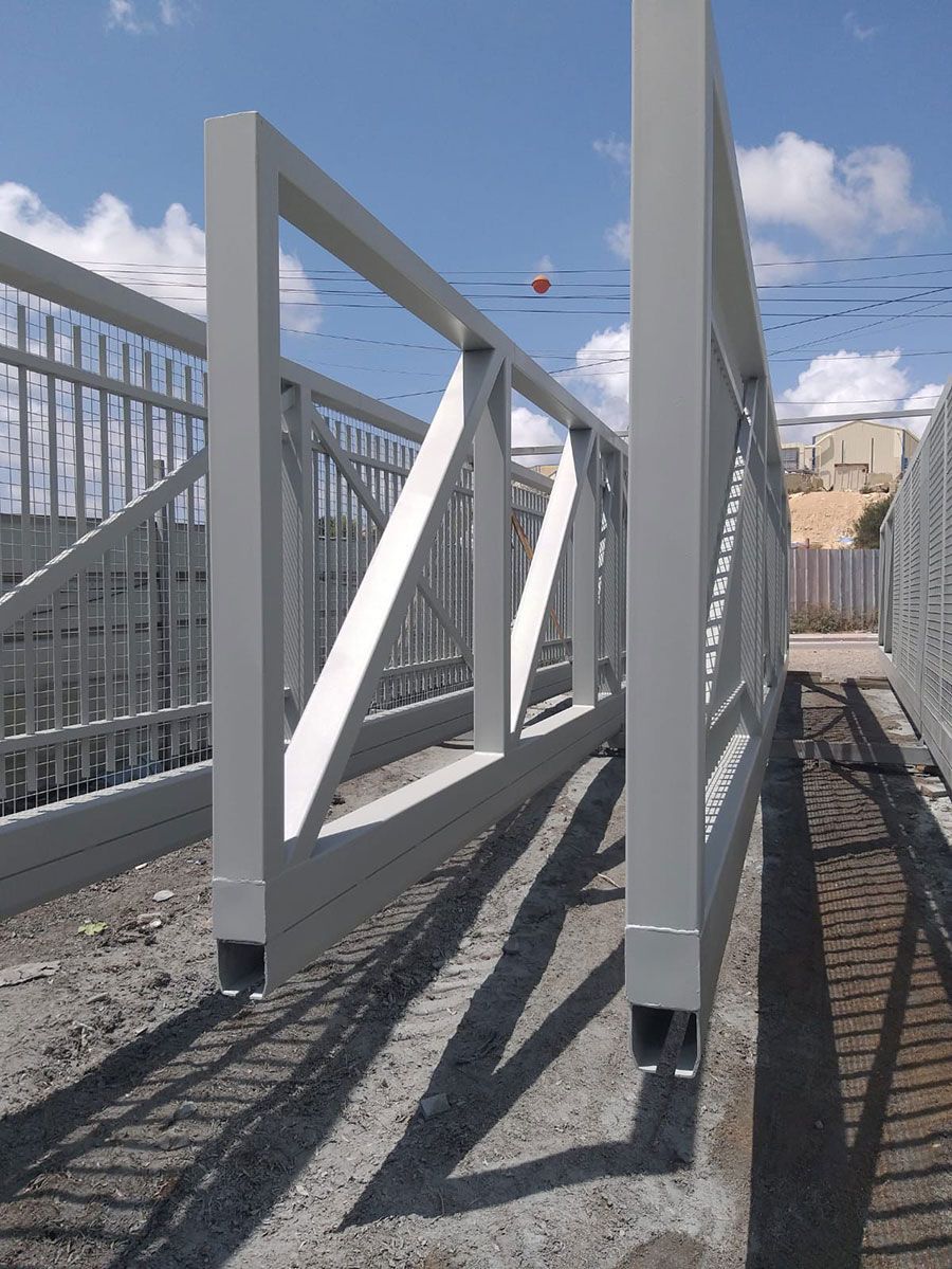 מבט מקרוב על קונסטרוקציית פלדה מסיבית המשמשת לבניית שערים חשמליים כבדים וקלים למפעלים ומוסדות.