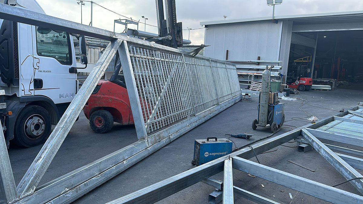 מסגרת מתכת ארוכה במיוחד לשער קונזולי בשלבי עבודה בחצר המפעל המייצר שערים חשמליים כבדים וקלים ליישובים ומפעלים.