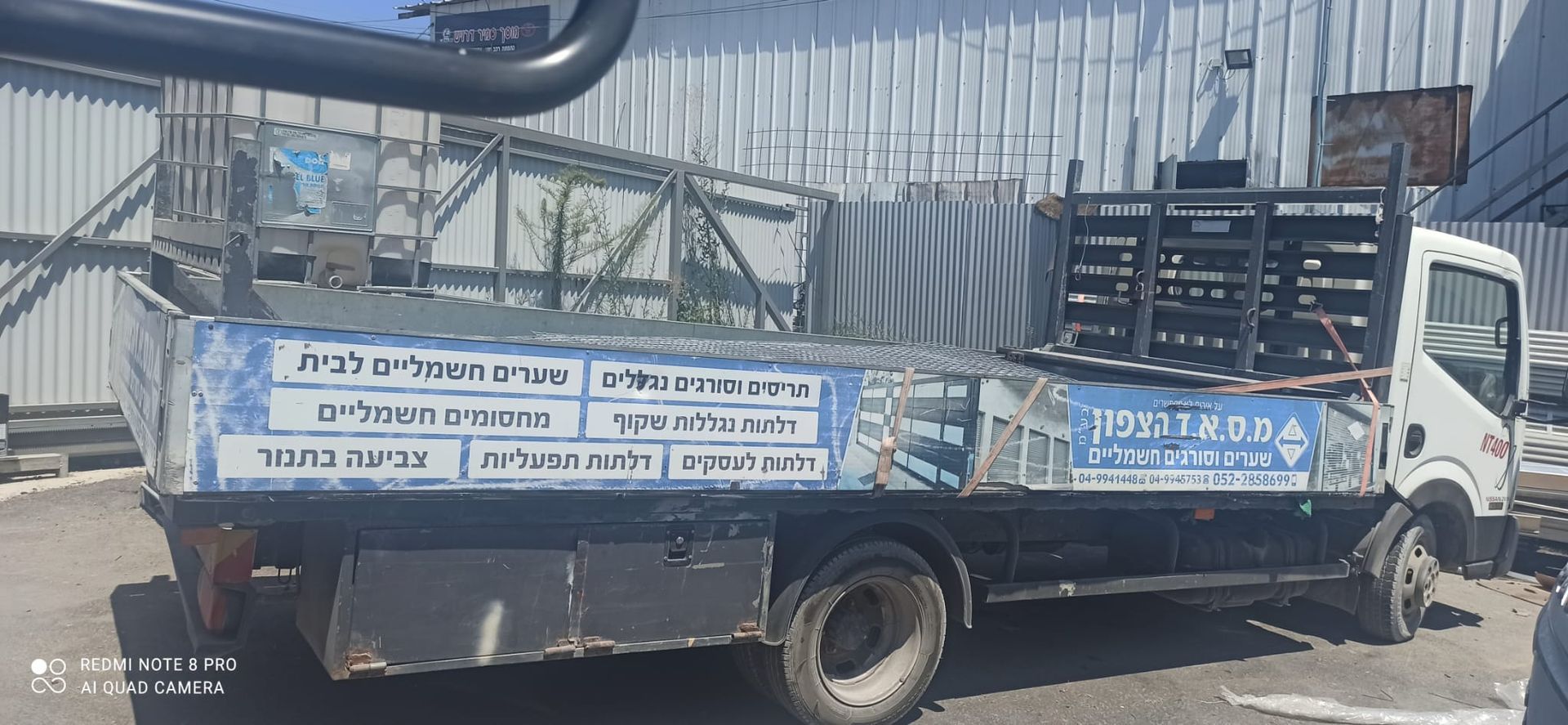 משאית אספקה של מ.ס.א.ד. הצפון עם שילוט המפרט את שירותי החברה, חונה מחוץ למבנה.