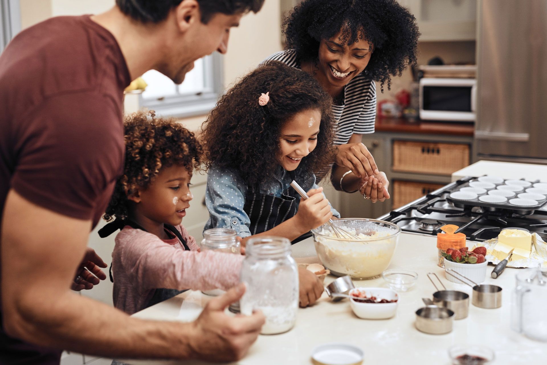 Family baking together at a kitchen counter, mixing ingredients and smiling around bowls and measuring cups