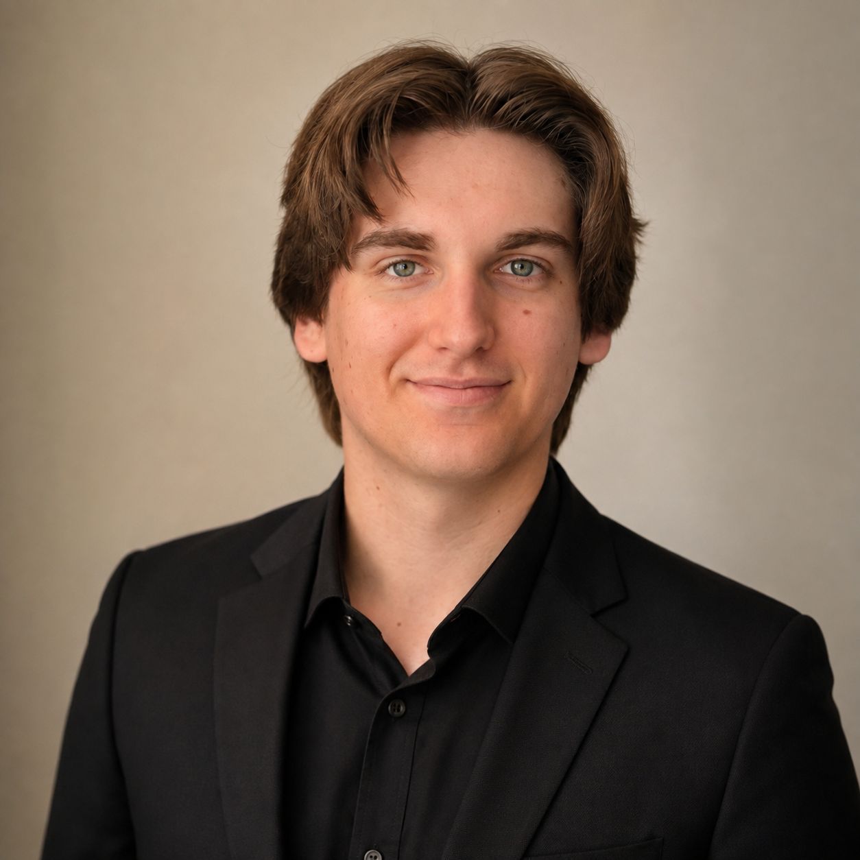 Portrait of a person in a black shirt and jacket against a beige background