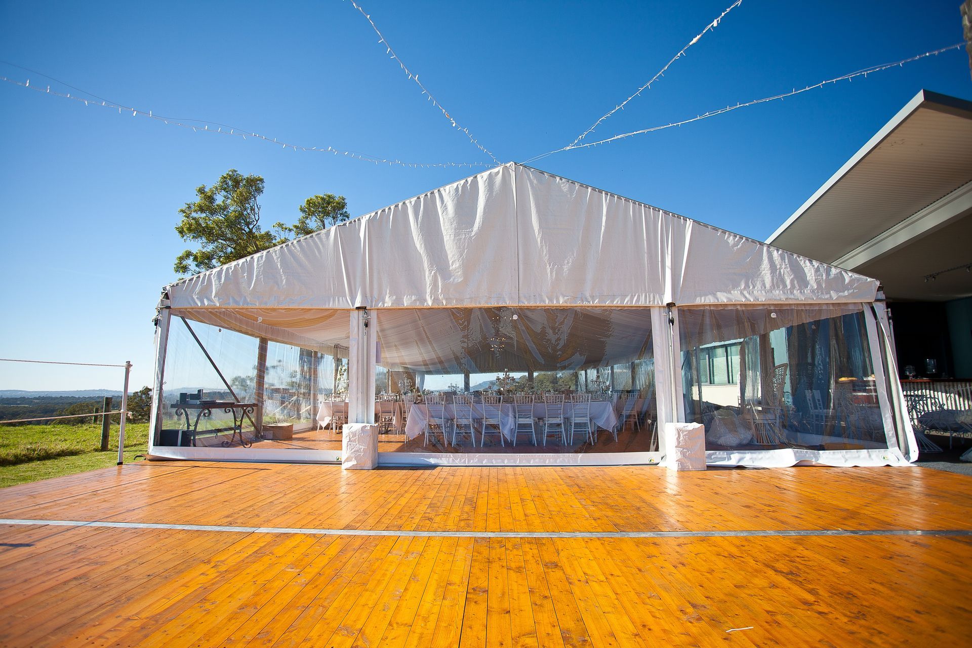 A large white tent with a wooden floor in front of it.