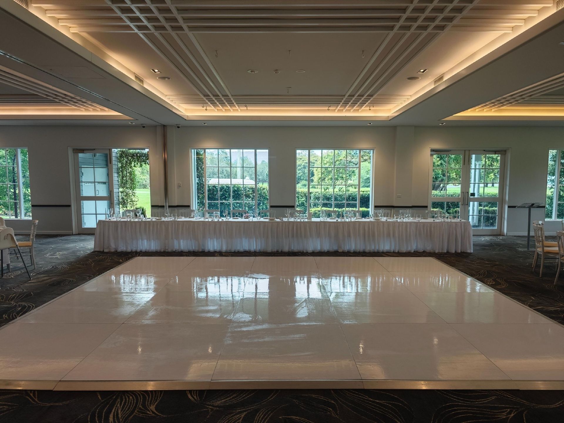 A large room with a dance floor and a long table.