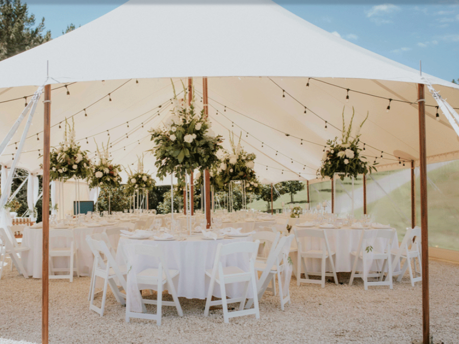 A large white tent with tables and chairs underneath it.
