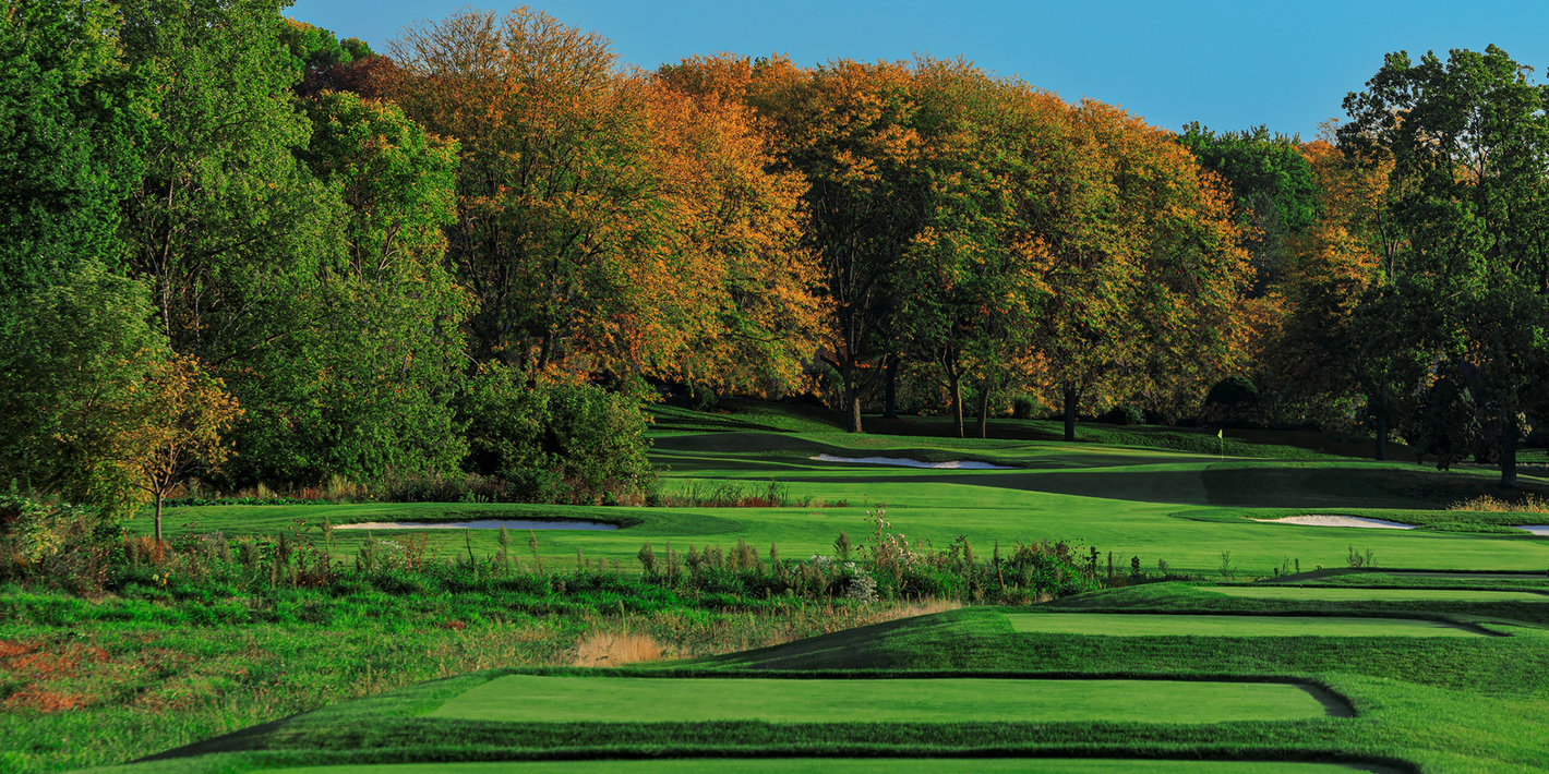 A golf course with trees in the background and a blue sky