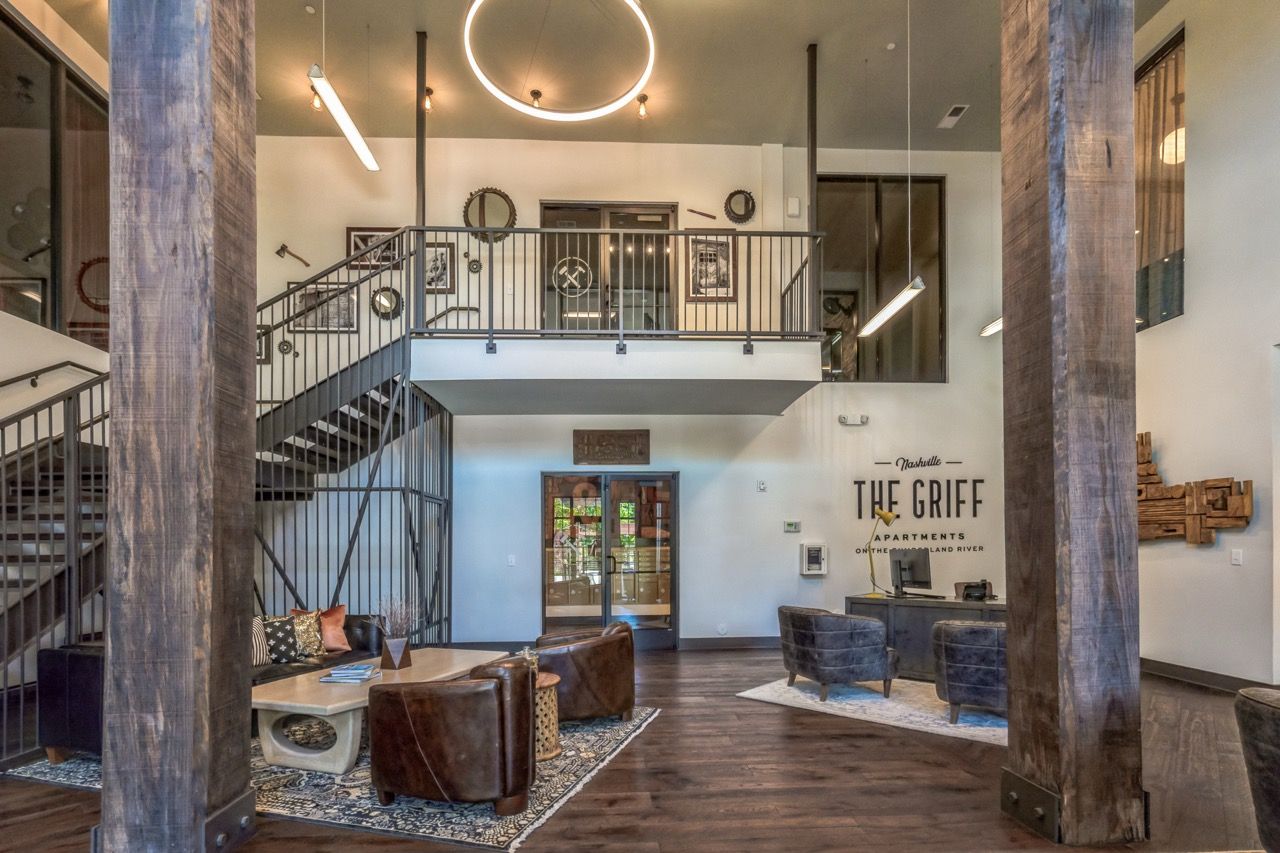 Open lobby with mezzanine, seating area, dark wood floors, modern decor, and a reception desk.