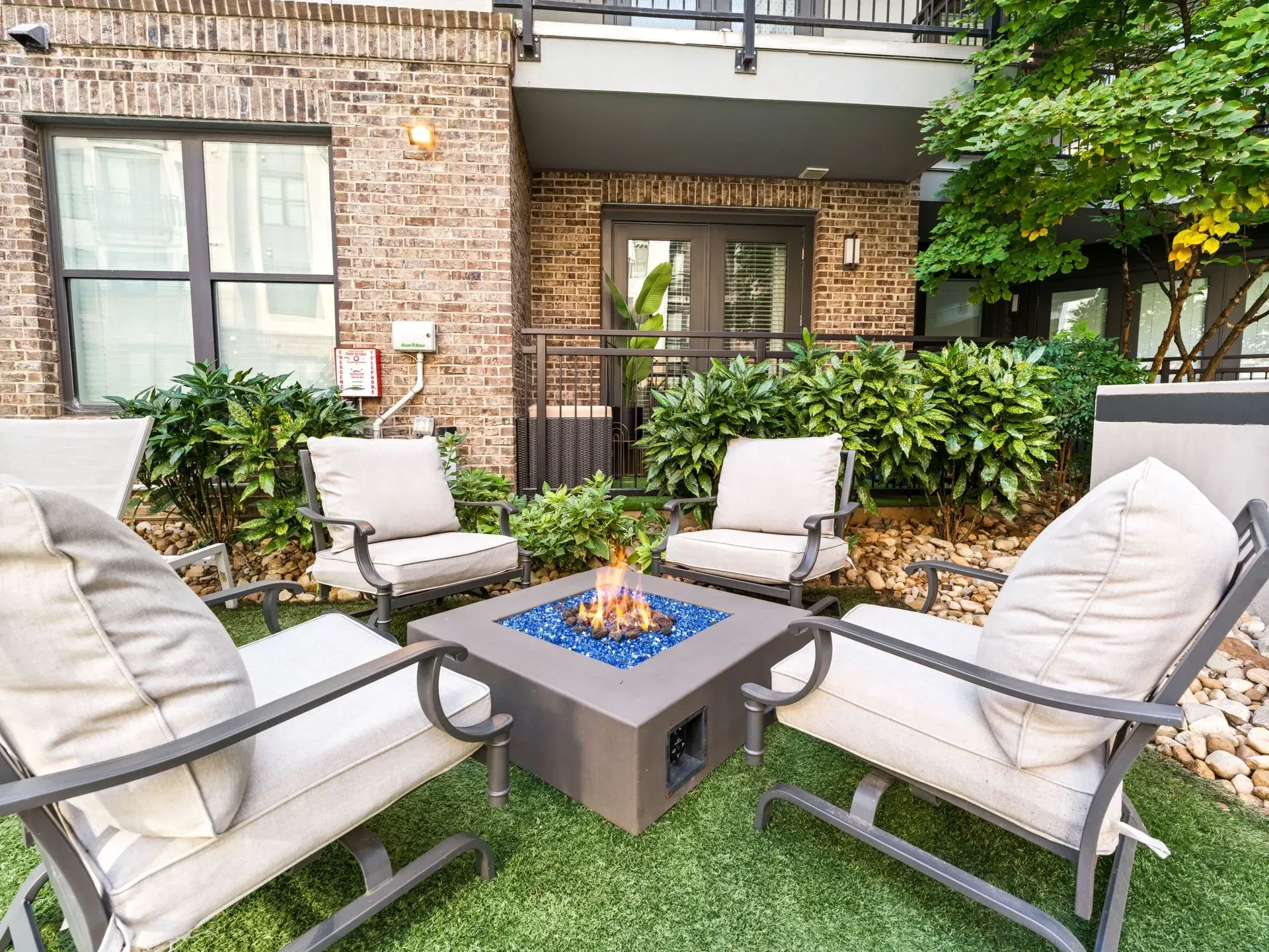 Patio seating around a square fire pit in front of a brick apartment building