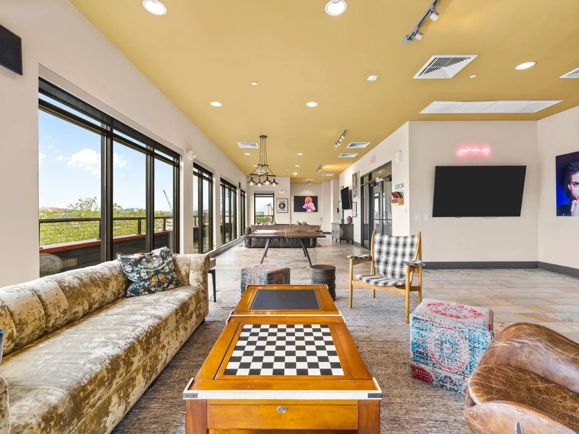 Bright modern lounge with couches, coffee tables, and large windows overlooking greenery