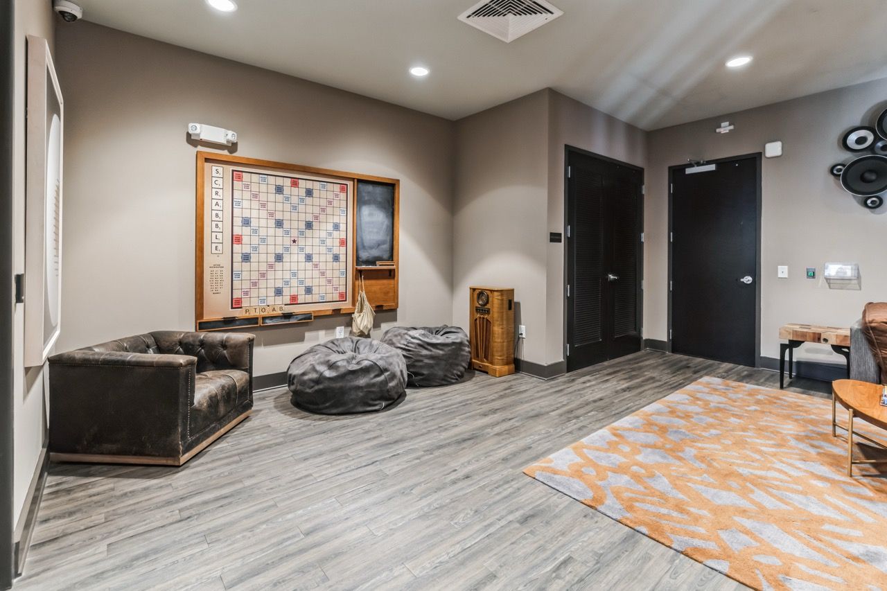 Interior community lounge with seating, bean bags, and a large wall game board.