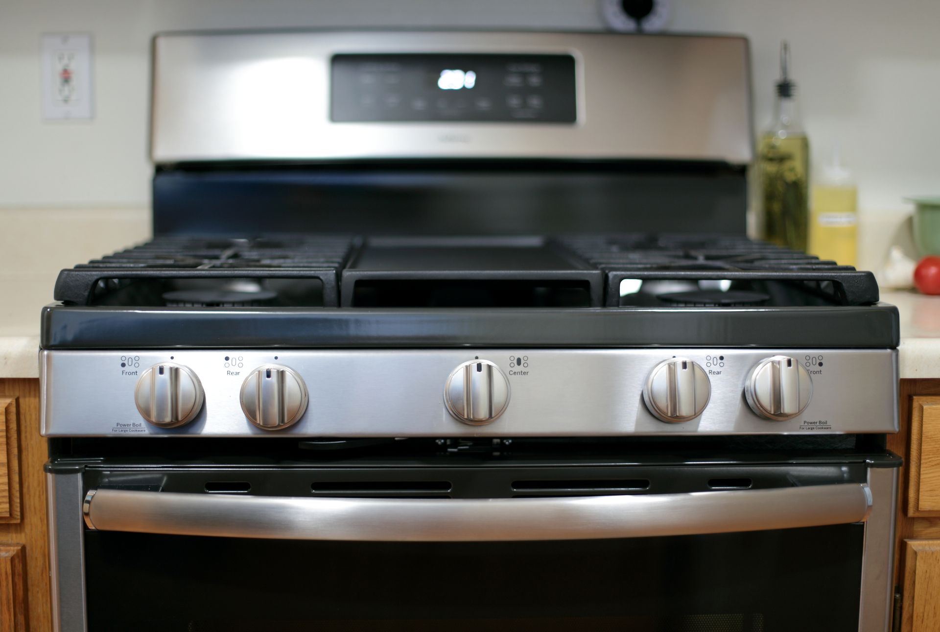 Stainless steel gas range stove with control knobs and burners in a modern kitchen.