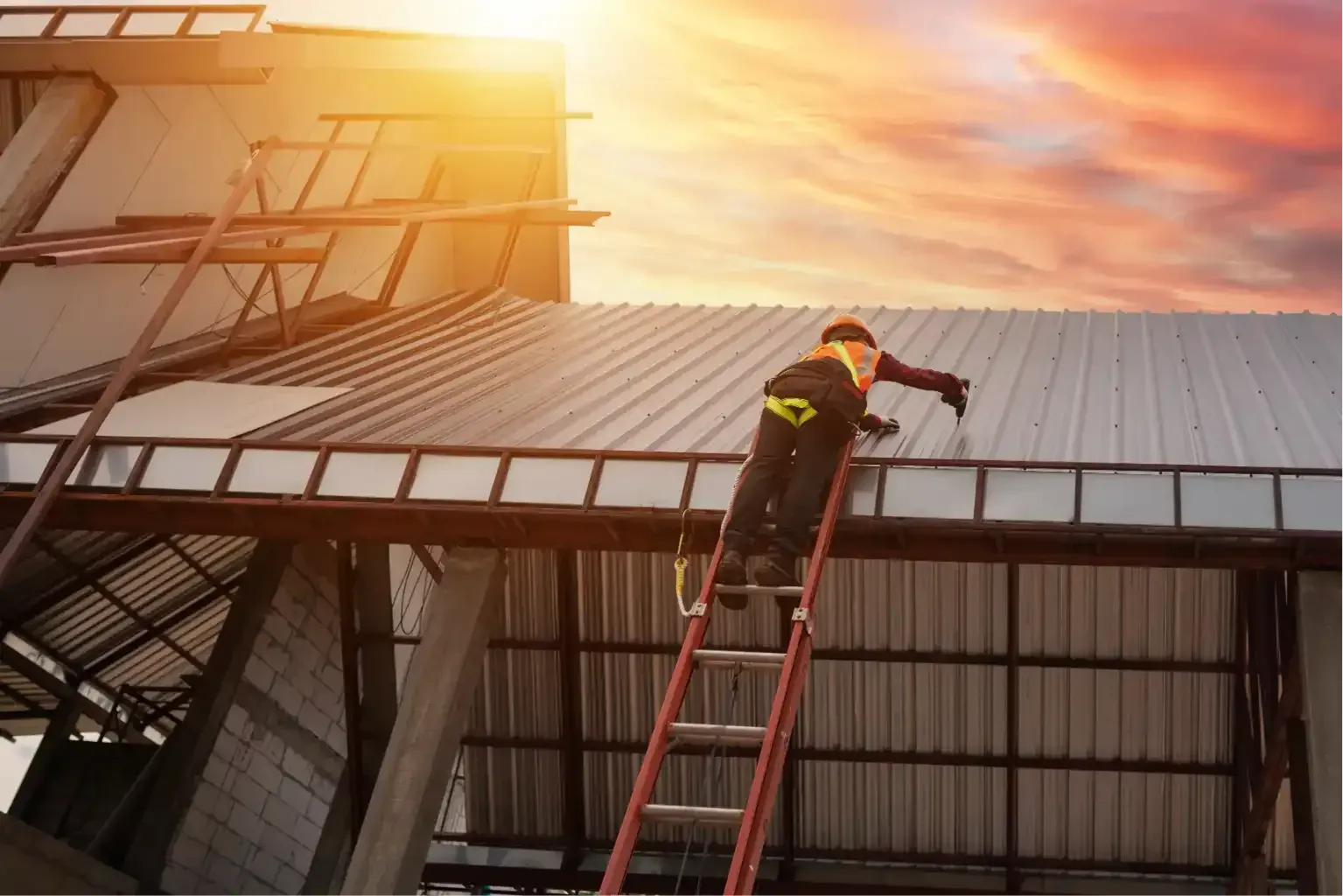 Roofing worker in blue hard hat and safety harness repairing terracotta roof tiles outdoors.