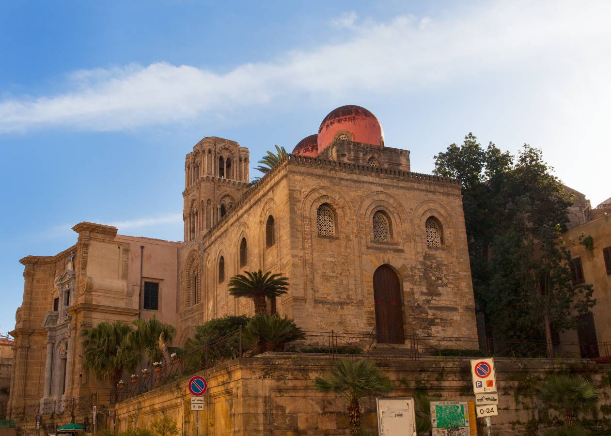 Église historique aux dômes orangés et aux détails de maçonnerie soignés, sous un ciel bleu.