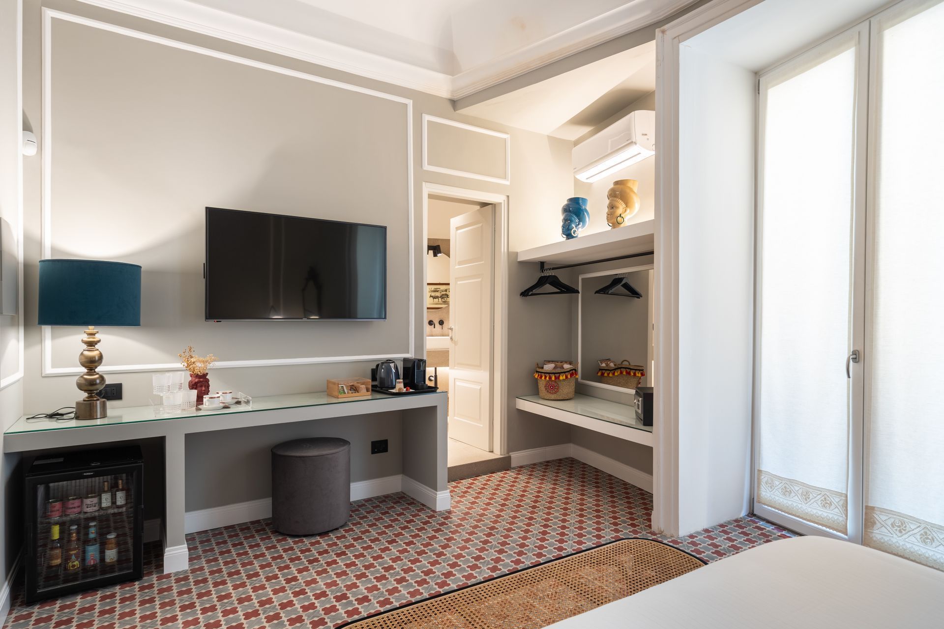 Camera d'albergo con TV, scrivania, armadio e minifrigo.