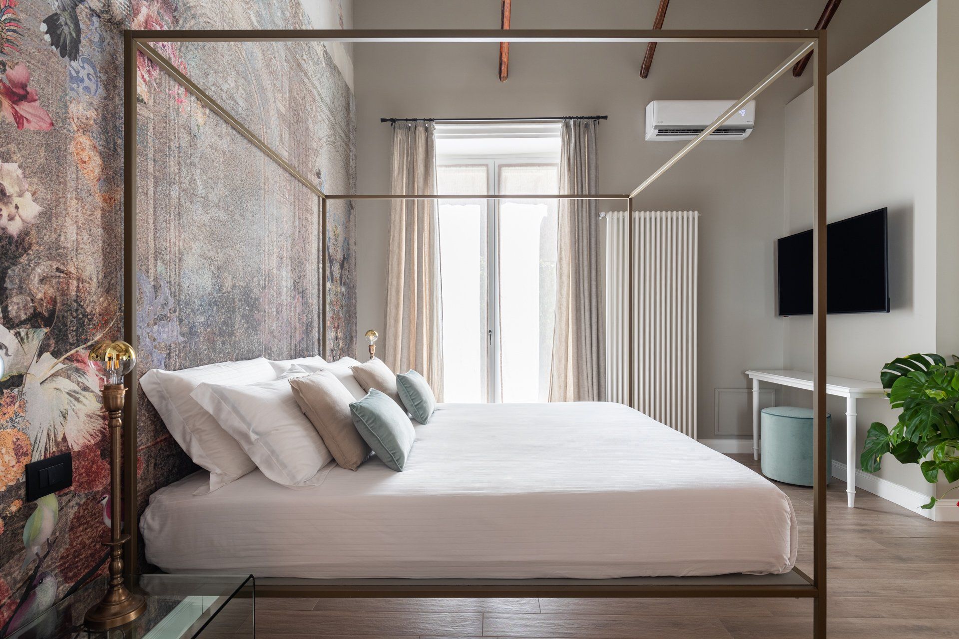 Camera da letto con letto grande, carta da parati floreale e colori neutri.