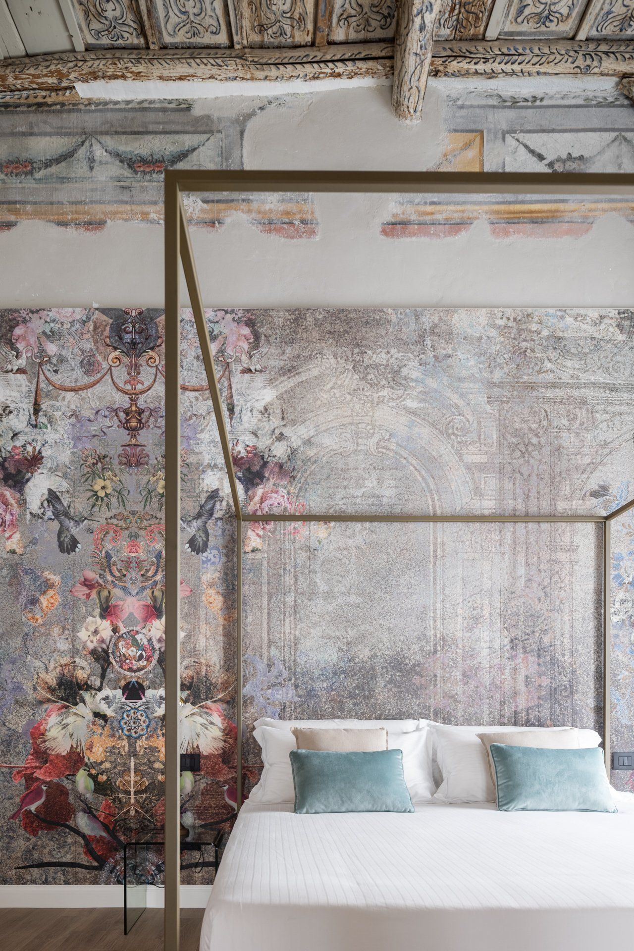 Camera da letto con letto a baldacchino e carta da parati floreale; soffitto antico e decorato.