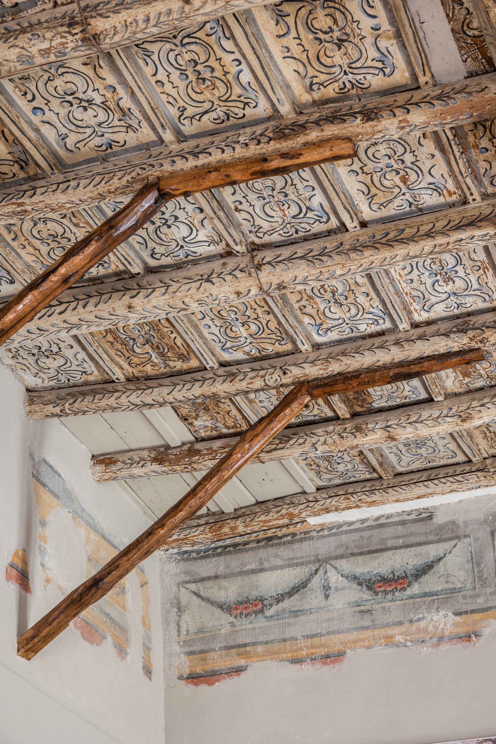 Soffitto decorato e dipinto con travi in ​​legno e murale decorativo sulla parete.