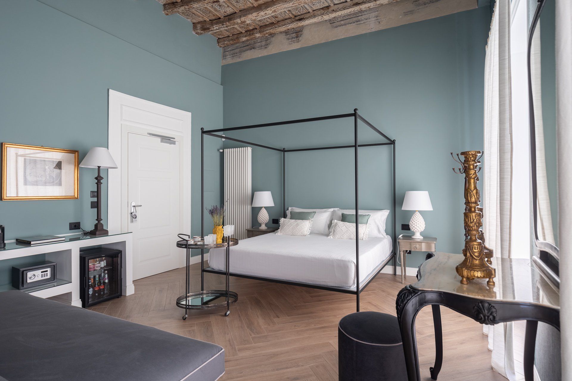 Camera da letto con letto a baldacchino, pareti color verde acqua, pavimento in legno e arredamento antico.