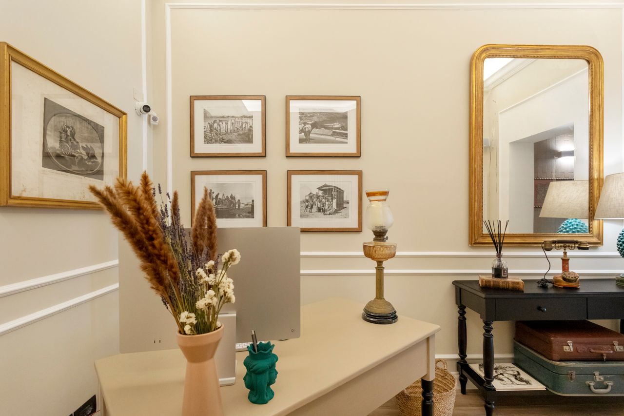 Un bureau intérieur avec des œuvres d'art, un bureau, un miroir et des éléments décoratifs.