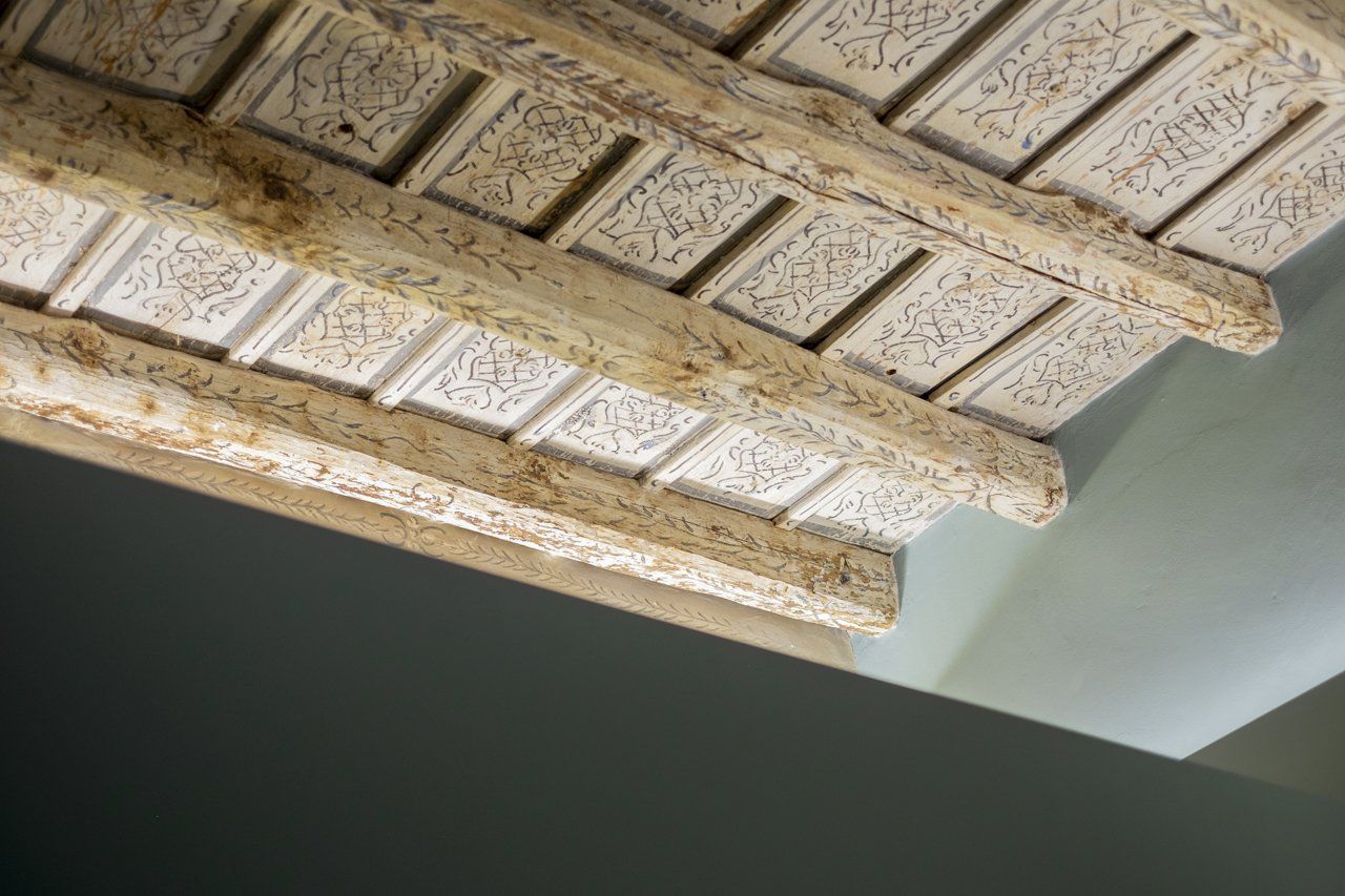Soffitto decorato e intagliato con travi in ​​legno e pannelli decorativi. Colori tenui.