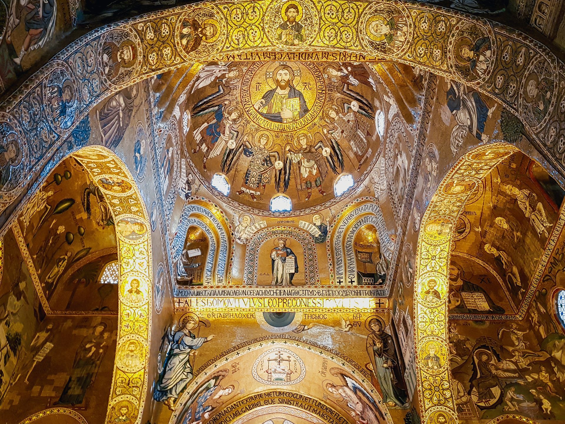 Mosaïques byzantines dorées à l'intérieur d'une église à coupole. Des détails et des motifs élaborés recouvrent le plafond et les arcades.