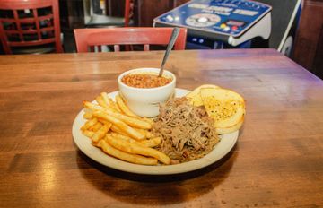 A plate of food with french fries and baked beans on a wooden table.