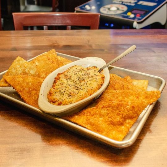 A tray of food with a bowl of dip and a spoon on it