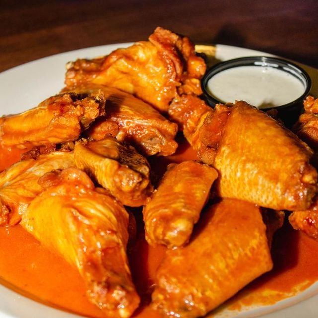 A white plate topped with chicken wings and a dipping sauce