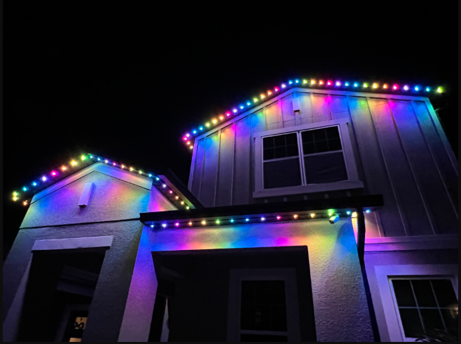 A house at night illuminated by colorful, rainbow-toned LED string lights outlining the rooflines and entryway. A house at night illuminated by colorful, rainbow-toned LED string lights outlining the rooflines and entryway.