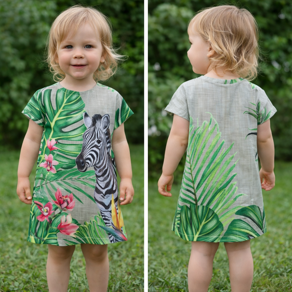 Peuter in groene jurk met jungleprint, van voren en van achteren gefotografeerd op het gras.