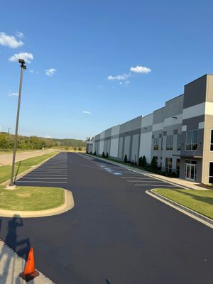 Empty paved road beside modern industrial buildings under a clear blue sky