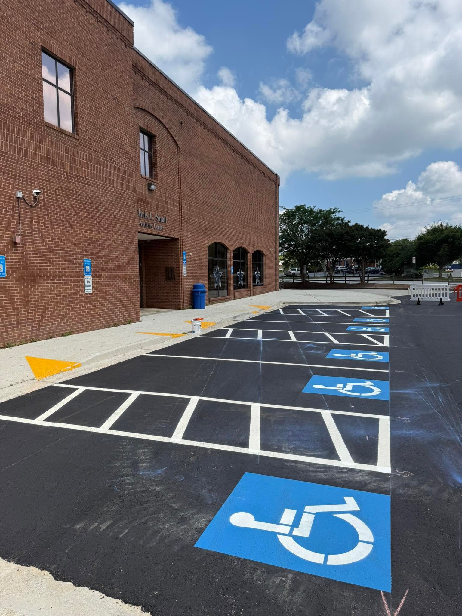Accessible parking spaces beside a brick building under a partly cloudy sky