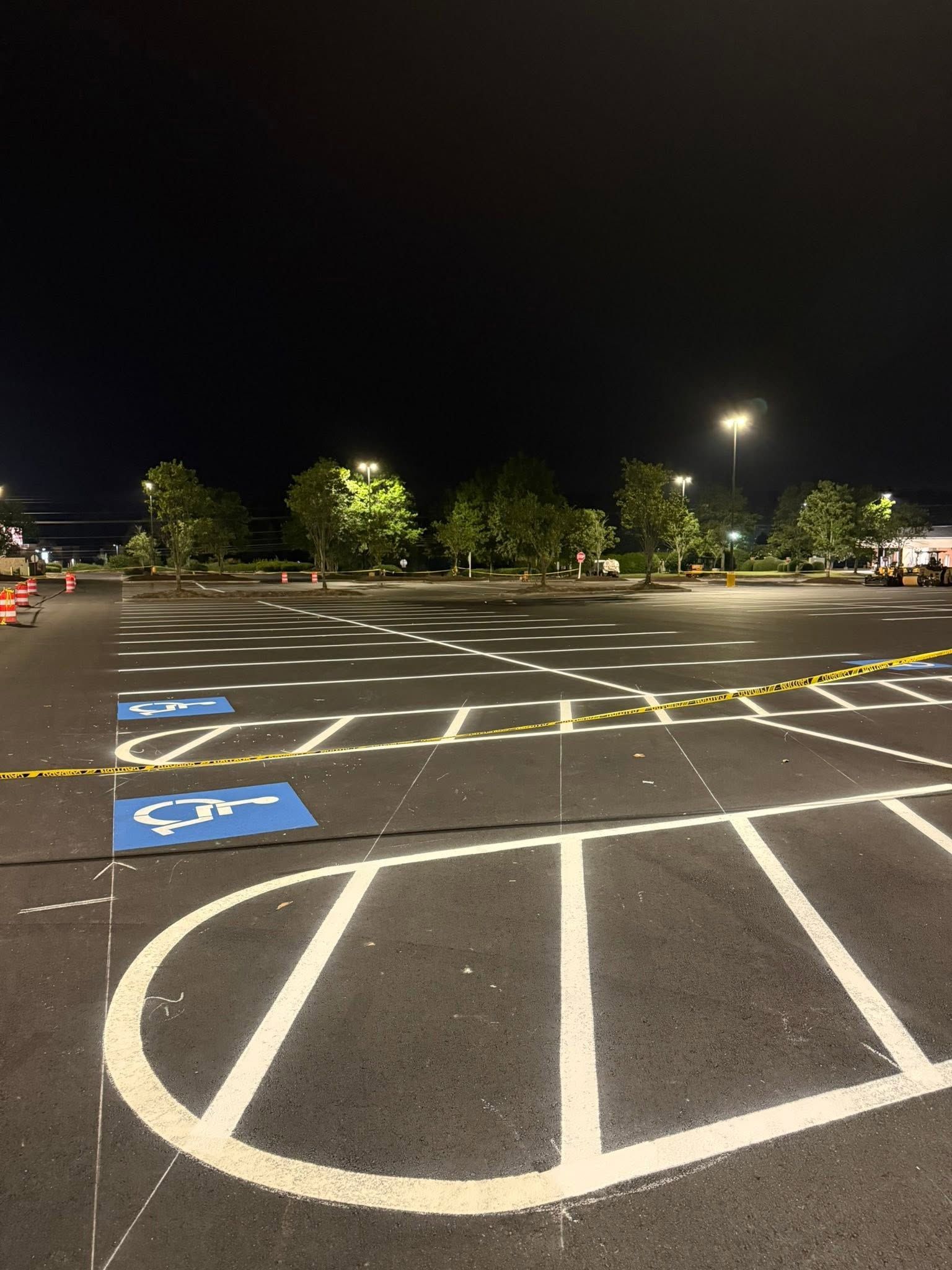Nighttime empty parking lot with blue accessible parking spaces and white painted lines