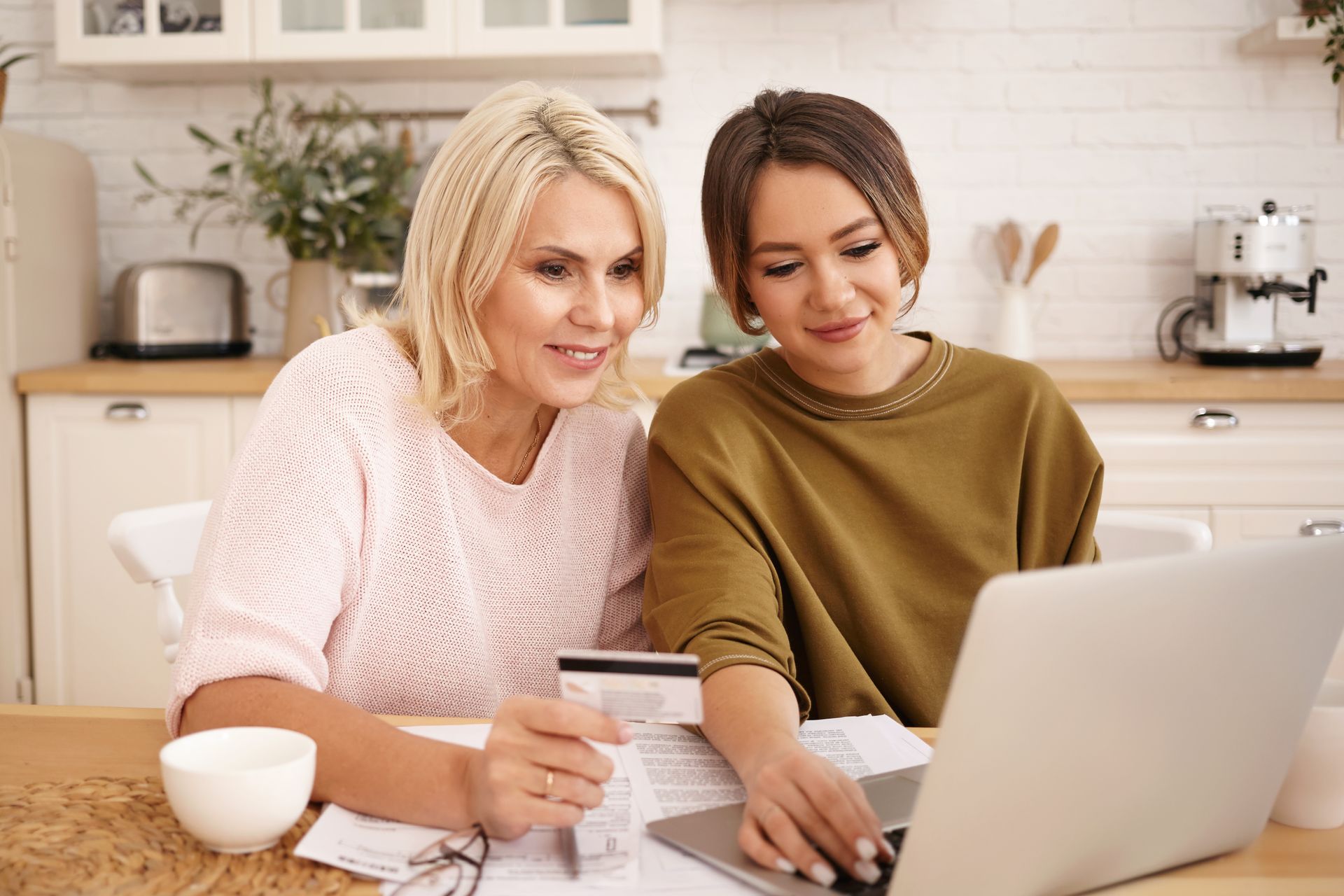 two people sitting at table looking at computer with credit card